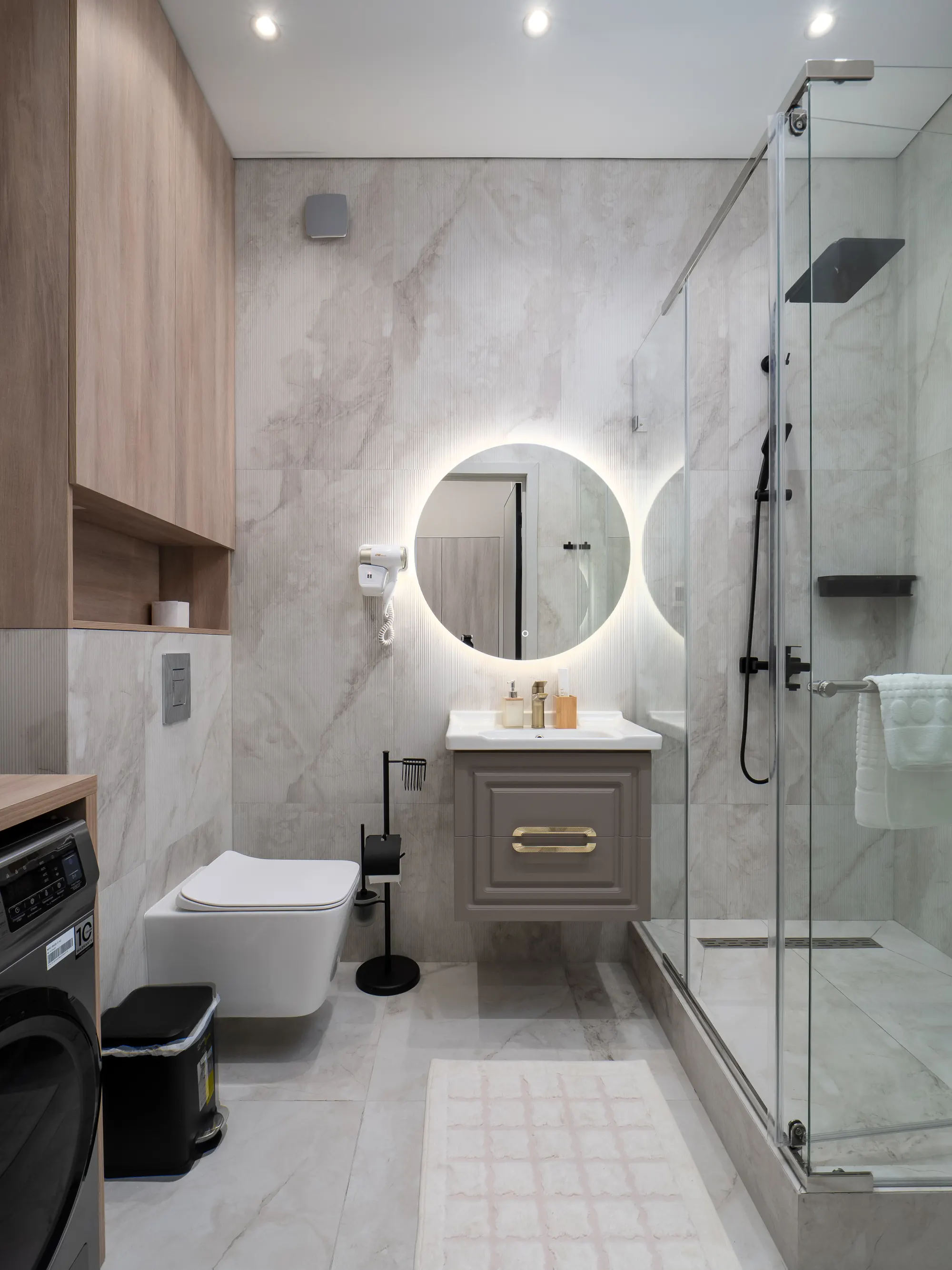 Marble bathroom with backlit round mirror